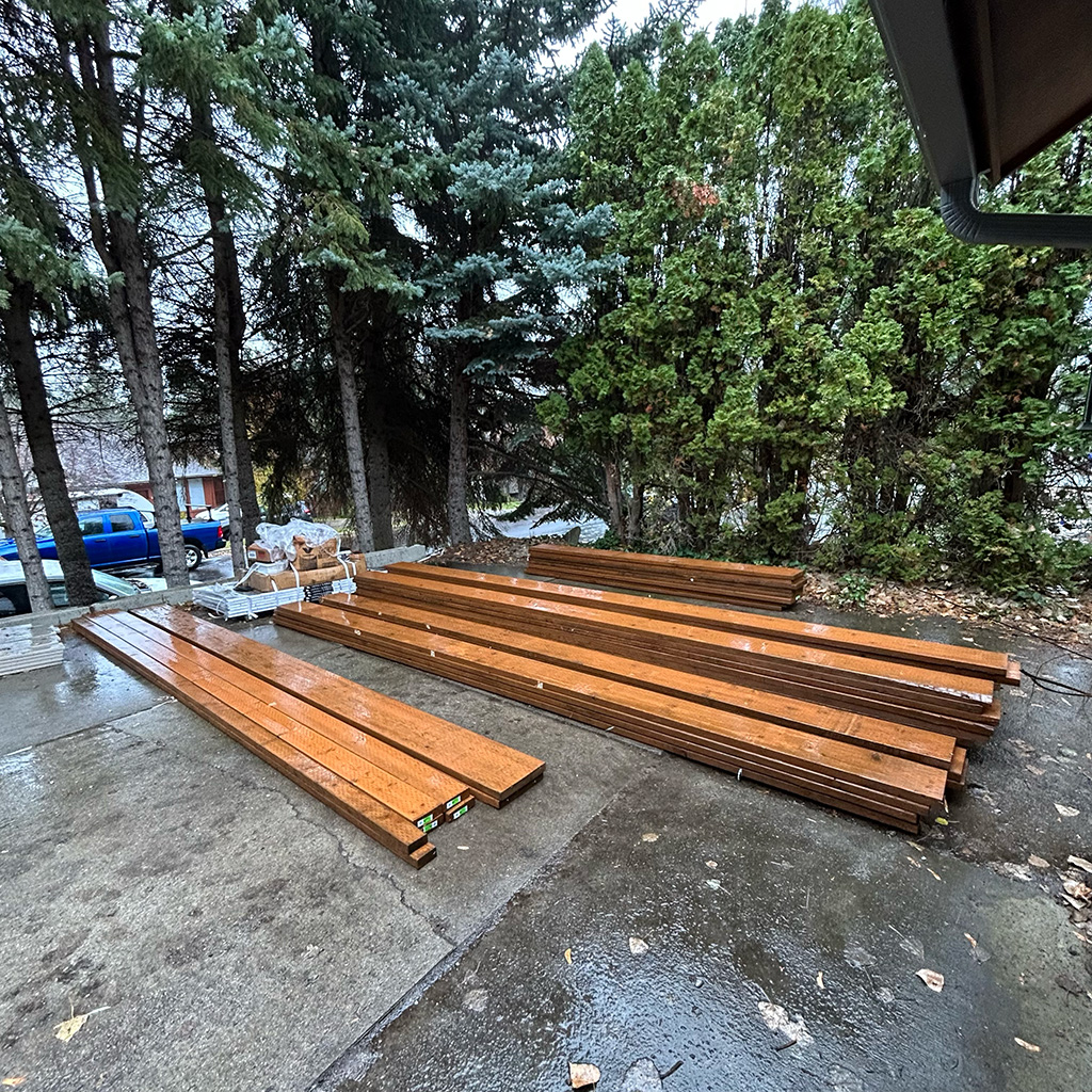 Pressure-treated lumber sorted and stacked on the ground for deck framing.
