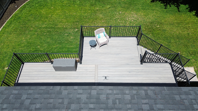 Drone shot of an elevated back deck with a bump-out, located on South Hill, surrounded by greenery.
