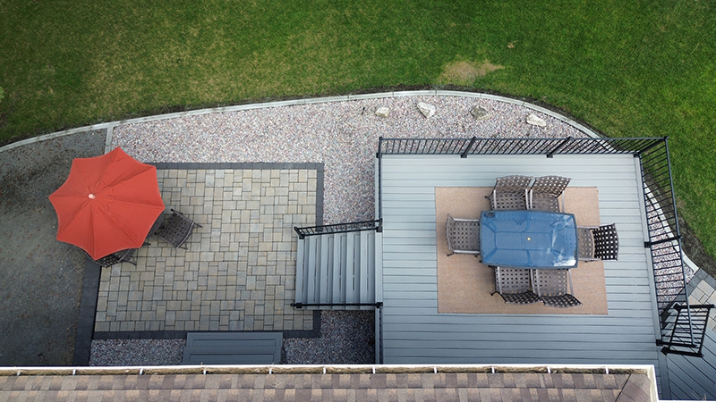 Drone shot showcasing a spacious deck that transitions seamlessly into a beautifully hardscaped patio, designed for outdoor living.