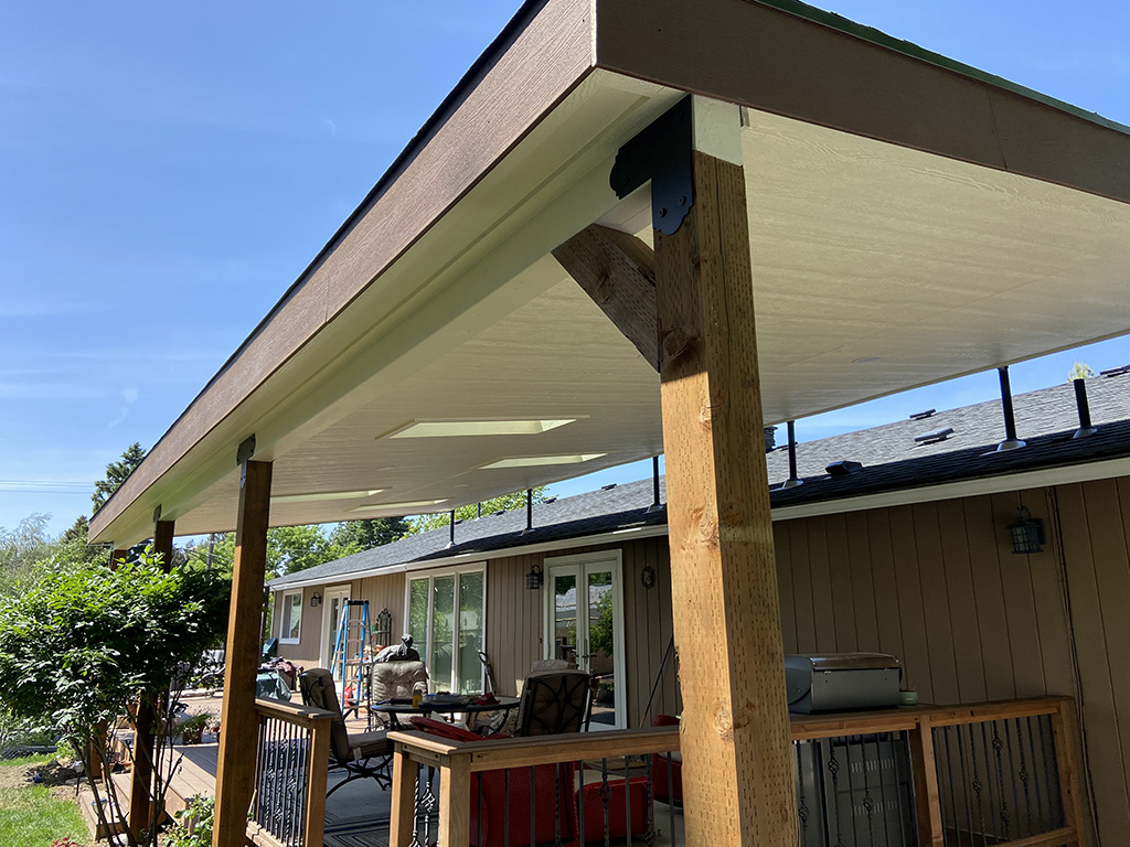 Lean-to roof cover with four staggered skylights over a back deck.