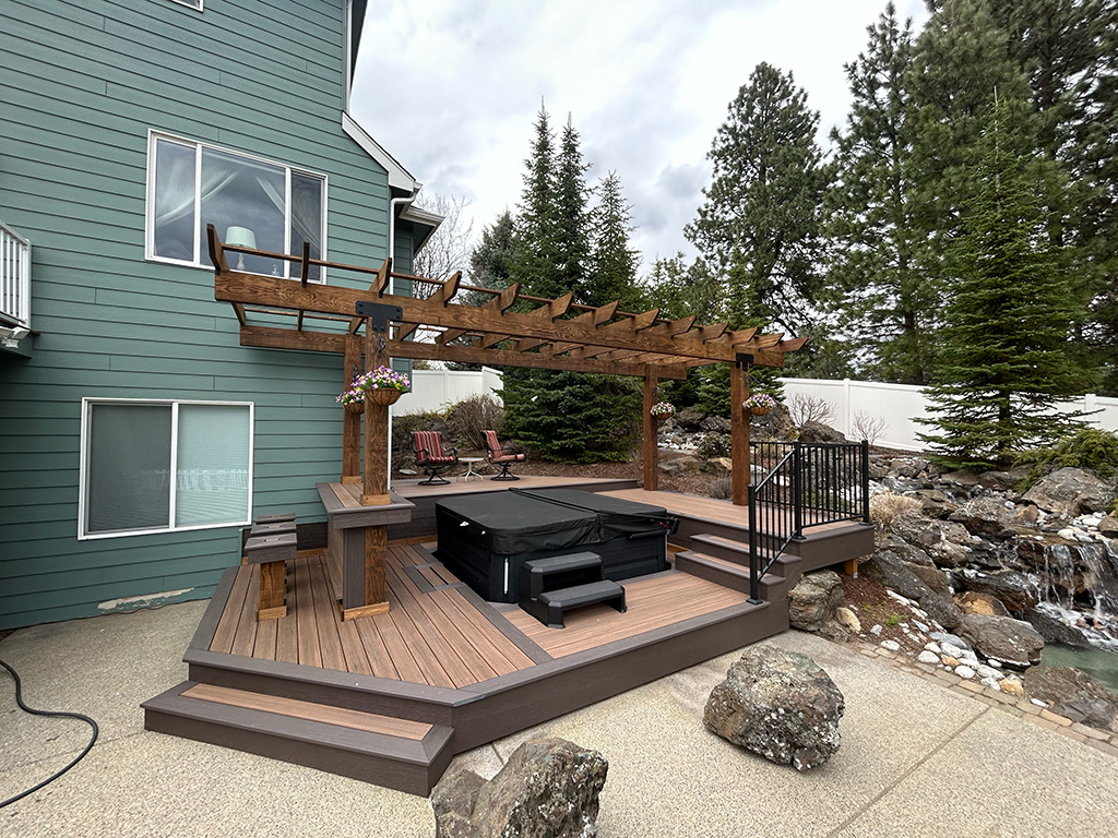 Multi-tier deck with a hot tub, bar seating, and a large pergola