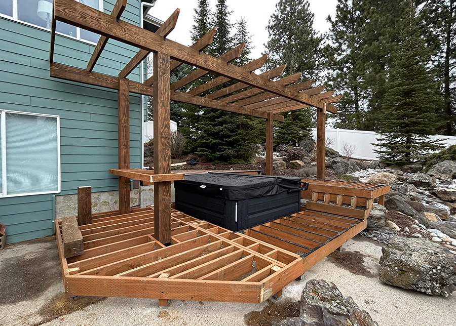 Framed multi-level deck with a hot tub, pergola, and bar table built using pressure-treated lumber.