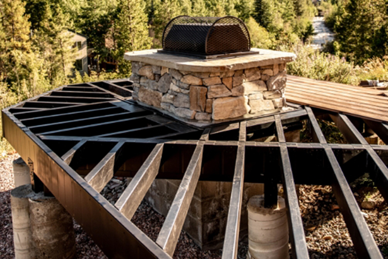 Deck framing around a stone outdoor kitchen grill using steel framing.