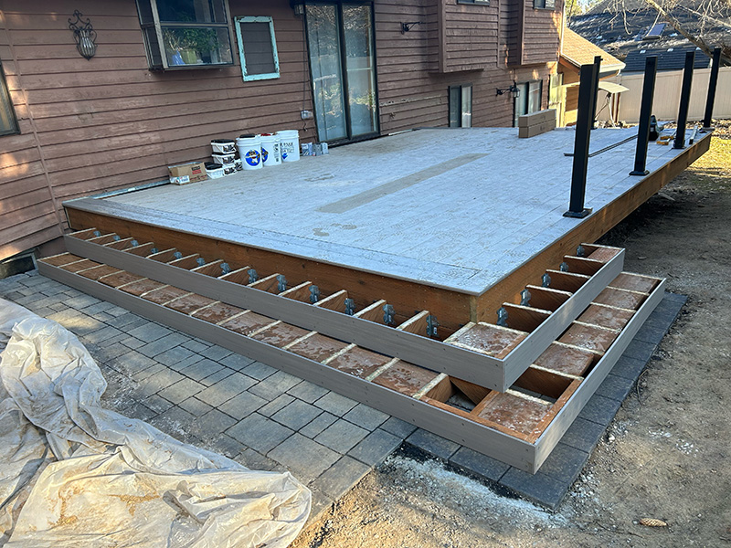 Deck stairs under construction in winter, with fascia, framed stringers, and blocking covered in frost.