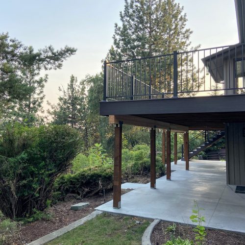 Built by Pacific Northwest Decks, this elevated composite deck includes a concrete patio below and black railing — a prime example of what the best deck builders in Spokane can deliver.