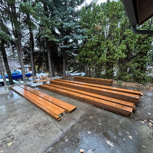 Pressure-treated lumber neatly stacked and ready for framing, ensuring a strong and durable deck structure.
